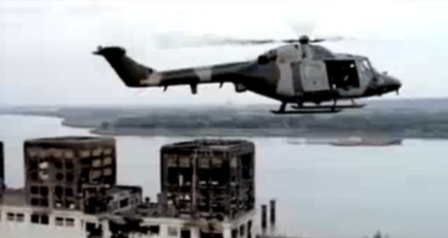 The band leaves the Gas works by helicopter, the distinct square buildings are visible in the background.